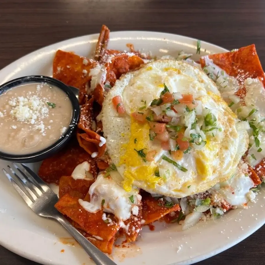 Chilaquiles rojos topped with two fried eggs, pico de gallo and queso fresco