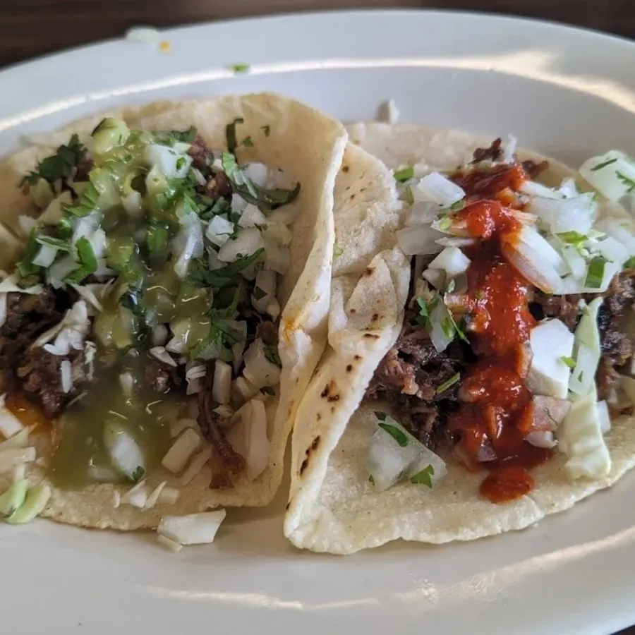 Two street tacos on fresh corn tortillas with salsa verde and salsa roja